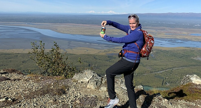 hiker on hill on top with beer